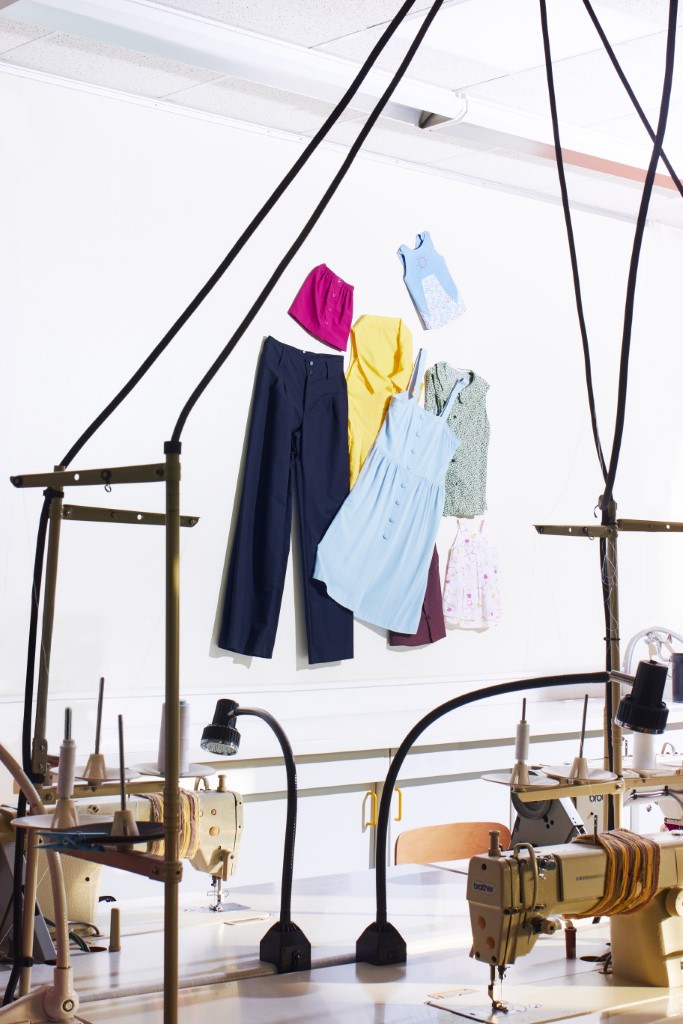 Lauréline Reynaud - Couture - Ensemble de vêtements multicolores sur mur blanc dans un atelier de couture professionnel